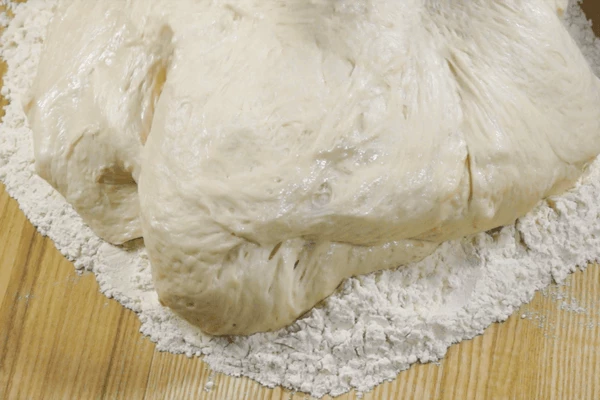 На рабочую поверхность высыпать муку на подпыл, в центр выложить подошедшее тесто, вымесить тесто, пока не перестанет прилипать к рукам. 