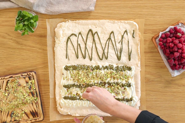 Меренгу выложить на доску с пергаментом. 
Отсадить крем, фисташковую пасту. Посыпать рубленными фисташками и миндальными лепестками.
