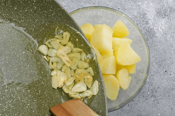 Чеснок нарезать пластиками, обжарить до золотистого цвета в оливковом масле. Добавить к картофелю.