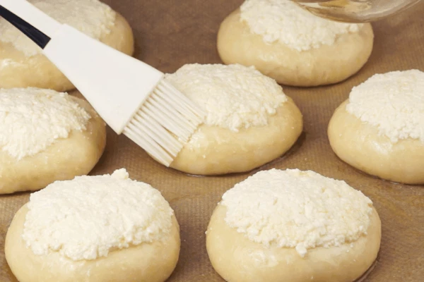 Выложить начинку в подготовленные углубления в шариках. Смазать тесто растительным маслом по периметру. Чтобы получилась глянцевая корочка, лучше смазать желтком.