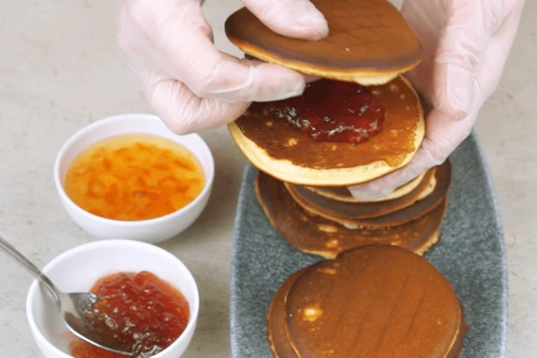 Готовые панкейки выложить на решетку и дать остыть. В центр выложить ложку джема, придавить вторым блинчиком. Если края получились неровные, то можно обрезать с помощью ножниц.