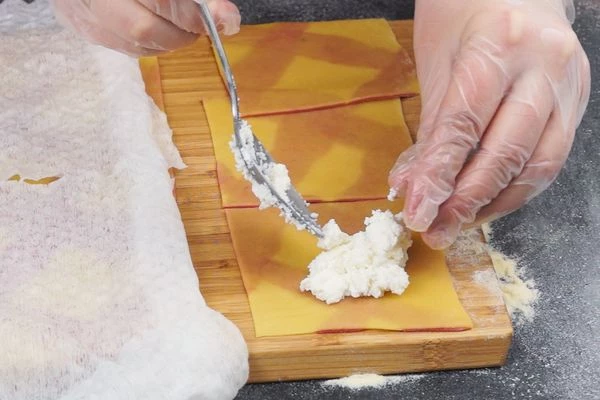 Разрезать цветное тесто на прямоугольники примерно 7*7 см. Чтобы тесто не подсыхало, сверху накрыть влажным полотенцем. Начинаем лепить: в центр выкладывать по 1 ст. л. начинки. 