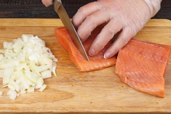 Далее готовим начинку: лук и чеснок мелко нарезать. Рыбу нарезать кубиком.