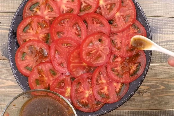 Помидоры помыть, нарезать тонкими кружочками, выложить на тарелку в один слой, полить заправкой. 