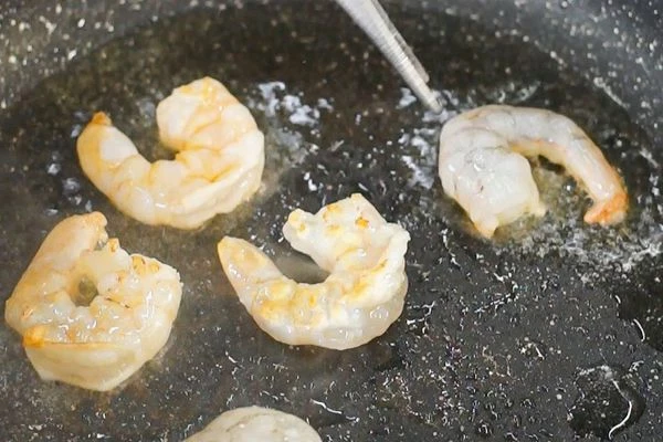 Креветки разморозить на нижней полке холодильника, обсушить на салфетке. Обжарить креветки на разогретой с маслом сковороде в течение 1 - 2 минут.