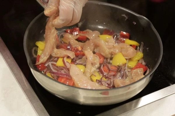 На разогретой с маслом сковороде обжарить лук и перец 1-2 минуты, добавить маринованную курицу, жарить до золотистого цвета.