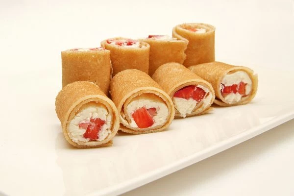 Выложить аппетитные блинные роллы на тарелку