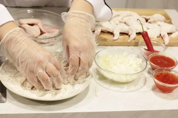 Охлажденные куриные крылья промыть, обсушить бумажным полотенцем. Замариновать в смеси соевого соуса, меда и горчицы на 5-10 минут. Затем обвалять в муке и дать постоять 5-7 минут, чтобы панировка хорошо прилипла.