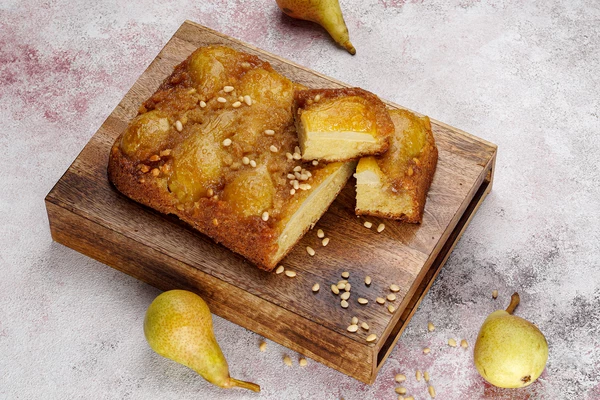 Готовый кекс перевернуть на тарелку, украсить кедровыми орехами. 