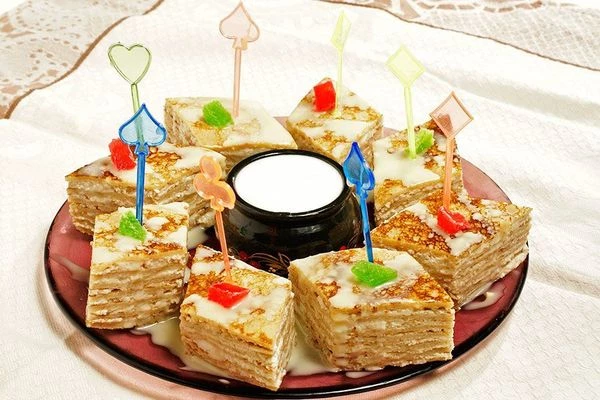 Разрезать слоеные блины на ромбики, украсить тонкой струйкой сгущенки, в центр воткнуть красивые шпажки. Подавать со сметаной.