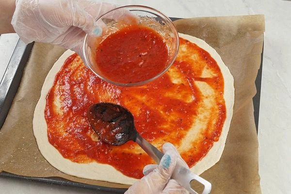 Смажьте соусом, оставляя примерно 1-1,5 см от края.