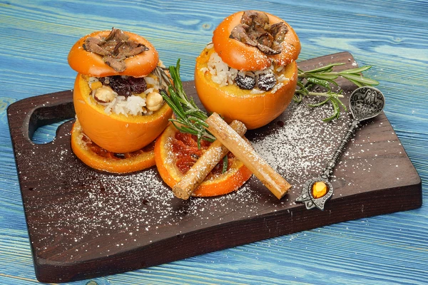 Готовую хурму выложить на тарелку, посыпать сахарной пудрой, украсить карамелизованным апельсином.