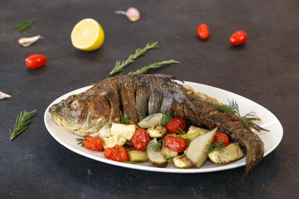 На блюдо для подачи переложить овощи, затем карпа. Оформить веточками укропа. Подавать с лимоном. Приятного аппетита!
