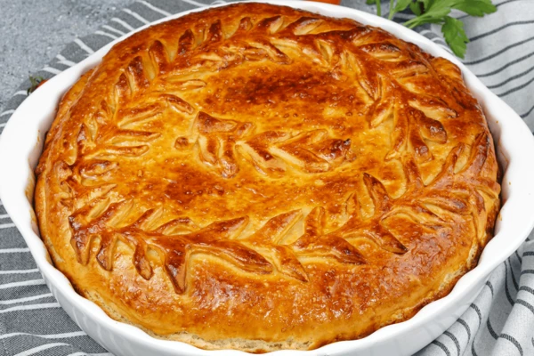 Поставить в разогретую до 190С духовку на 40-60 минут (в зависимости от мощности вашего оборудования время приготовления может меняться). Если снизу пирог еще не готов, а верх уже подрумянился, накройте сверху листом пергамента.