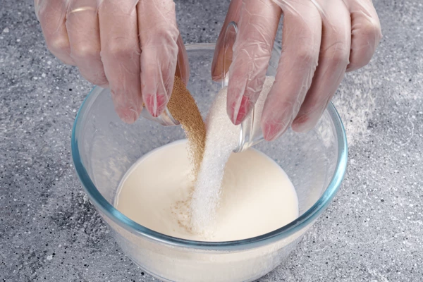 Замесить тесто: молоко подогреть до 30С, добавить сахар (30 г) и дрожжи, размешать до растворения сахара.