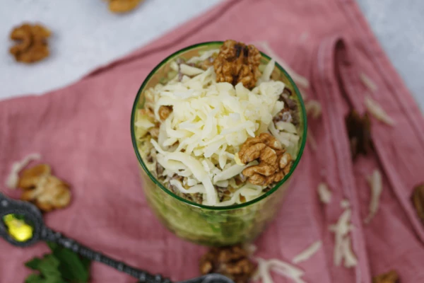 Готовый салат украсить тертым сыром и орешками.