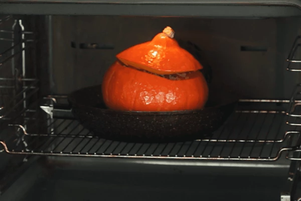 Тыкву поставить в форму, накрыть тыквенной крышкой, поставить в разогретую до 180С духовку минут на 40. Готовую тыкву подать со свежей зеленью. Можно украсить веточкой свежего розмарина или тимьяна.