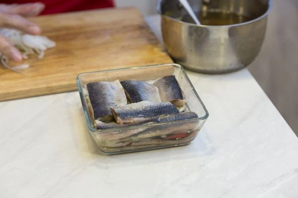 Филе сельди уложить в один слой в глубокую форму,затем сверху положить лук, нарезанный полукольцами, еще слой сельди, лук и залить маринадом, чтобы закрыло всю рыбу.