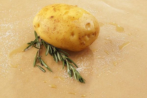 Картофель промыть, выложить на смазанный смесью оливкового масла и соли пергамент. Рядом положитт веточку розмарина.