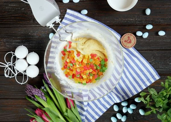 Добавить просеянную муку. Вымесить с помощью крючкообразных насадок в течение 7-10 минут. Всыпать цукаты, хорошо перемешать. Накрыть пленкой, убрать в теплое место на 1,5-2 часа. 