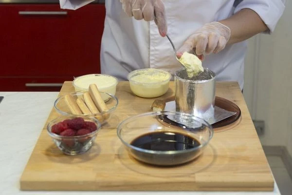 На центр тарелки поставьте форму для десерта. В нее выкладывайте слоями: половинки печения савоярди, смоченные в кофе, сыр, взбитый с сахарной пудрой, ягоды, чередуйте слои, пока форма не заполнится. Верхний слой закройте сыром.