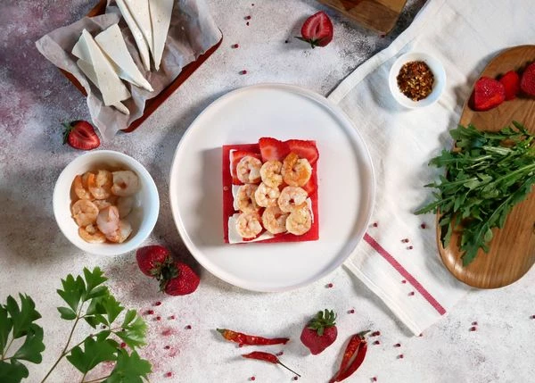 Креветки разморозить, обжарить в течение 2 минут на масле с чесноком и тимьяном, посолить, разрезать пополам. Выложить на клубнику.
