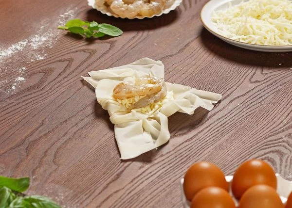  Выложить на эту часть натертую моцареллу и креветки.