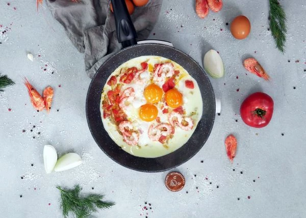 Отделить желтки от белков. В сковороду к овощам влить белки, жарить 1-2 минуты. Сверху аккуратно выложить желтки и очищенные креветки. Жарить еще 1 минуту при минимальном нагреве. Можно в этот момент накрыть крышкой.