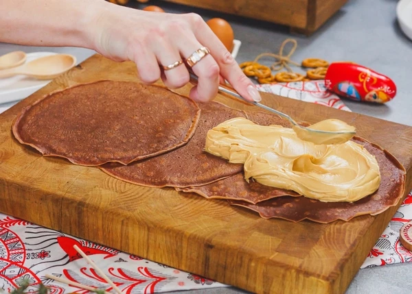 На доску выложить блинчики внахлест. По середине намазать начинку. 
