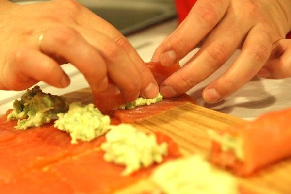 Аккуратно выложите получившуюся смесь на полоски семги и сверните небольшие рулетики.