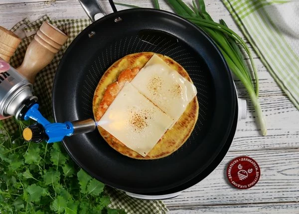 Положить 2 ломтика сыра, опалить их горелкой, снять питу с огня.