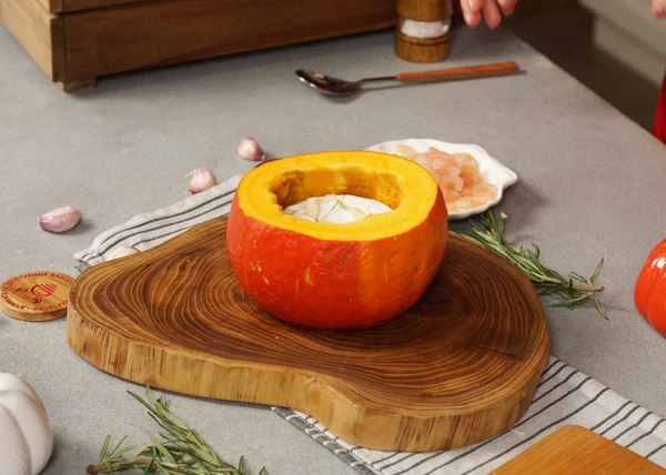 В камамбере сделать надрезы и вставить в них ломтики чеснока. Сыр выложить в середину тыквы. 