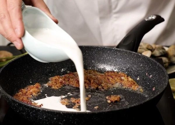 В глубокой сковороде нагреть масло на среднем огне и добавить нарезанный лук, чеснок и имбирь. Жарить 2-3 минуты. Добавить мисо пасту и жарить еще 2 минуты, чтобы паста слегка карамелизовалась. Влить кокосовые сливки, дать закипеть и готовить 4-5 минут. 
