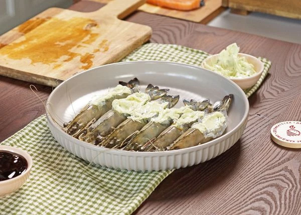 Подготовленные креветки выложить в форму для запекания спинкой вверх. Нафаршировать их маслом. 