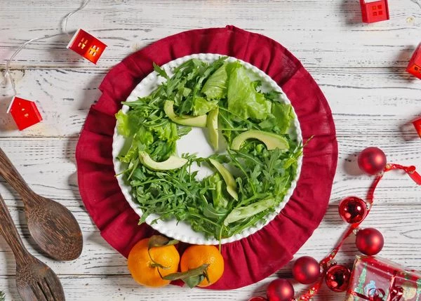 На тарелку для подачи выложить листья салата. Сверху выложить ломтики авокадо.