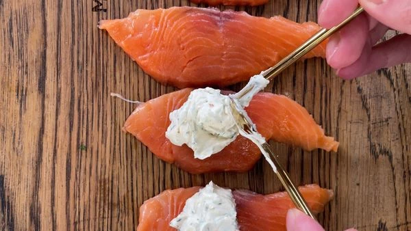 Слайсы чавычи  разложить на доске. На каждый слайс выложить творожный сыр. Аккуратно свернуть в рулетики. 
