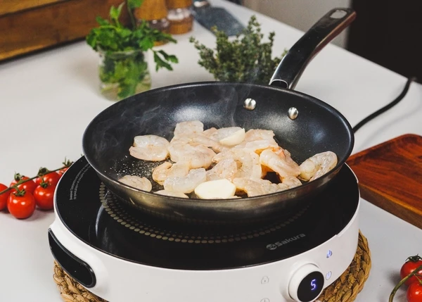 В этой же сковороде с добавлением масла обжарить размороженные креветки в течение 1,5 минут.