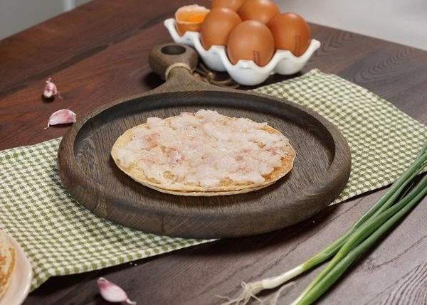 Блинчики разморозить на нижней полке холодильника. На пергамент выложить 2 блинчика, смазать мягким сливочным маслом. На них выложить начинку из минтая. 