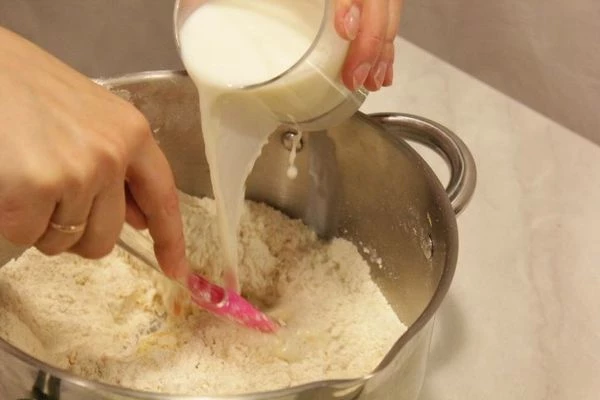 Влить теплое молоко. Замесить тесто.