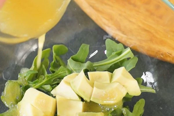 Авокадо очистить от кожуры, нарезать крупным кубиком, смешать с рукколой и соусом, который сделали ранее.