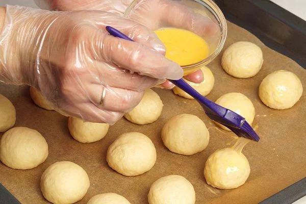 Готовое тесто разделить на колобки нужного размера ( у нас колобки диаметром 4 см). Выложить их на  смазанный маслом пергамент, смазать каждый взбитым яйцом. Поставить в разогретую до 200С духовку на 15-25 минут. 