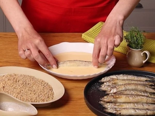 В миске смешать яйцо и молоко. Обмакнуть каждую рыбку сначала в эту смесь.
