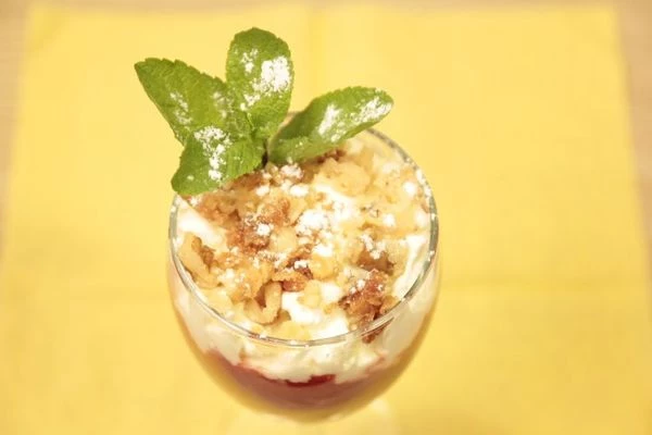 Выложить клубничную пасту в бокал, украсить взбитыми сливками, сливочно-ореховой крошкой и веточкой мяты.