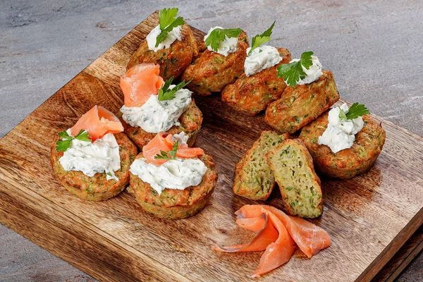 Готовые кексы украсить творожным сыром с зеленью и ломтиками красной рыбы.