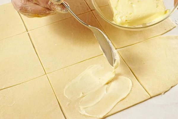 Разрезать на прямоугольники примерно 10*10 см. Смазать мягким сливочным маслом.