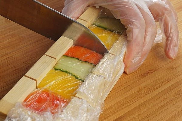 Разрезать готовые прессованные суши по специальным меткам острым ножом.