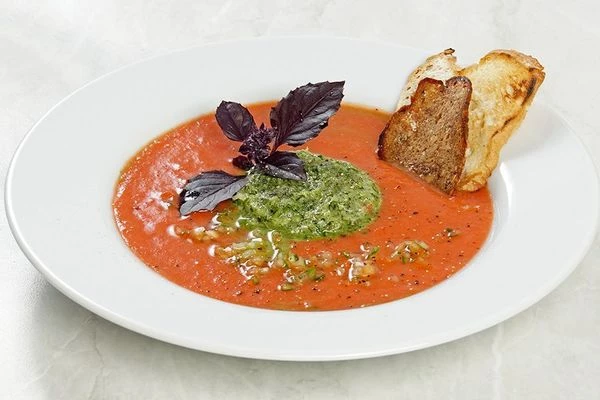 В центр тарелки выложить зеленое пюре с помощью кулинарного кольца, вокруг налить гаспачо. Украсить веточкой базилика и гренками. Можно добавить несколько капель соуса табаско (можно просто смешать томатный суп с огуречным пюре).