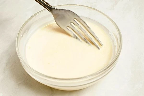 К желткам влить сливки и хорошо размешать.