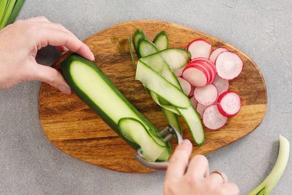 Редис нарезать кружочками. Огурец нарезать длинными полосками.