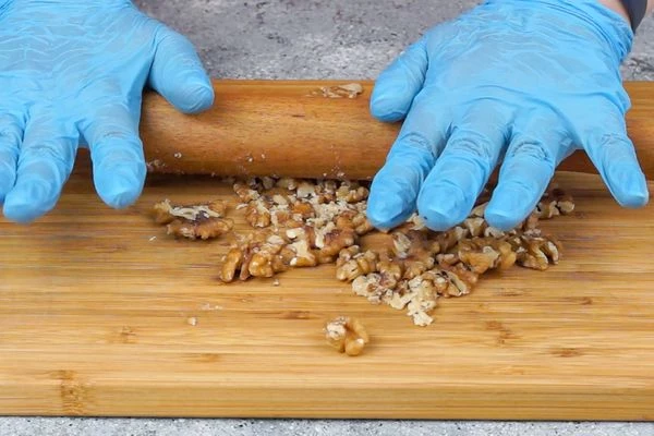 Орехи измельчить скалкой до крупной крошки.